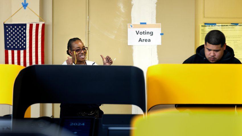 Election worker Theresa Johnson, left, cheers on a voter after he casts his ballot on Super Tuesday at Avalon Carver Community Center in South Los Angeles on March 5, 2024.