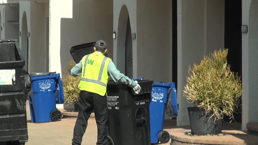 A Waste Management worker is seen emptying a trash bin at the Villa Espana townhouse complex in Encino, where the monthly fees for trash and recycling collection may increase by more than 500% in September.